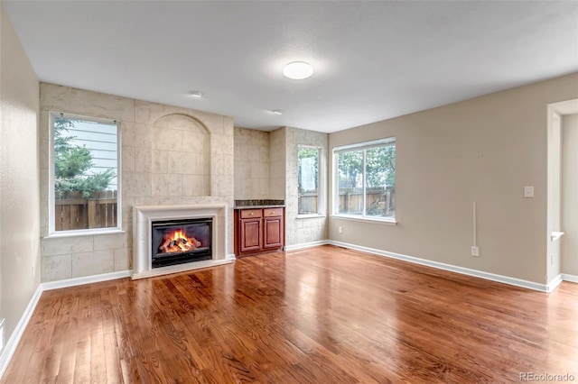 12047 W Coal Mine Dr, Littleton, CO 80127 - unfurnished living room with a tiled fireplace, wood finished floors, and baseboards