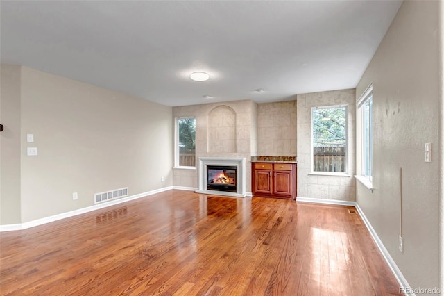 12047 W Coal Mine Dr, Littleton, CO 80127 - unfurnished living room with baseboards, light wood-style flooring, visible vents, and a glass covered fireplace