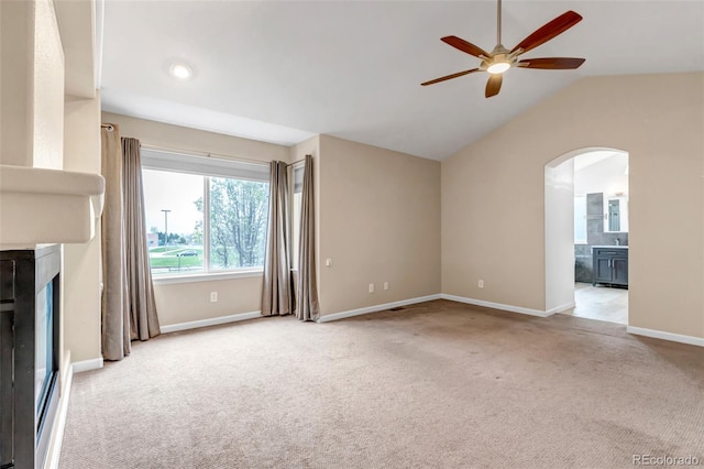 12047 W Coal Mine Dr, Littleton, CO 80127 - unfurnished living room with a fireplace, baseboards, ceiling fan, arched walkways, and light carpet