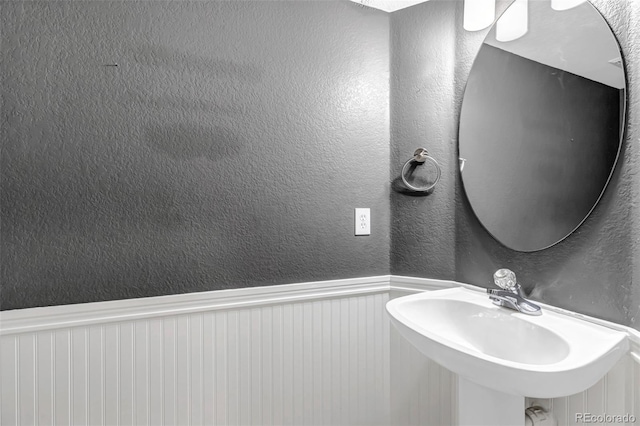 12047 W Coal Mine Dr, Littleton, CO 80127 - bathroom featuring a sink, a textured wall, and a wainscoted wall