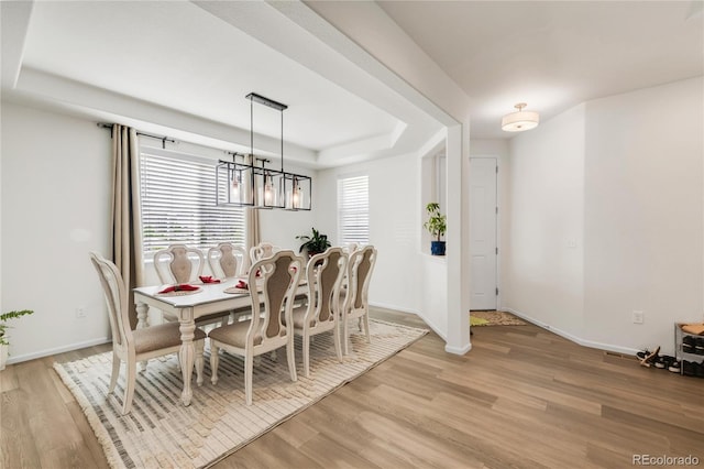 27986 E Frost Pl, Aurora, CO 80016 - dining area featuring light wood finished floors, a tray ceiling, and a chandelier