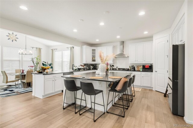 27986 E Frost Pl, Aurora, CO 80016 - kitchen with wall chimney range hood, freestanding refrigerator, dark countertops, a kitchen island, and recessed lighting