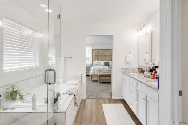 27986 E Frost Pl, Aurora, CO 80016 - full bath with double vanity, wood finished floors, a bath, a shower stall, and connected bathroom