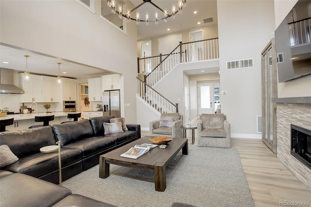 11142 Bright Sky St, Littleton, CO 80125 - living area with light wood finished floors, a towering ceiling, a chandelier, stairway, and a fireplace
