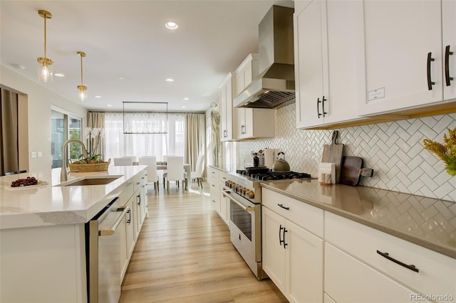11142 Bright Sky St, Littleton, CO 80125 - kitchen featuring a sink, appliances with stainless steel finishes, wall chimney exhaust hood, light wood-style flooring, and white cabinetry