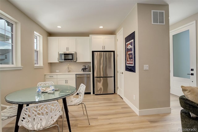 11142 Bright Sky St, Littleton, CO 80125 - kitchen featuring appliances with stainless steel finishes, light wood-style floors, backsplash, white cabinetry, and recessed lighting