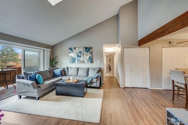 living room with high vaulted ceiling, light hardwood / wood-style floors, and beamed ceiling