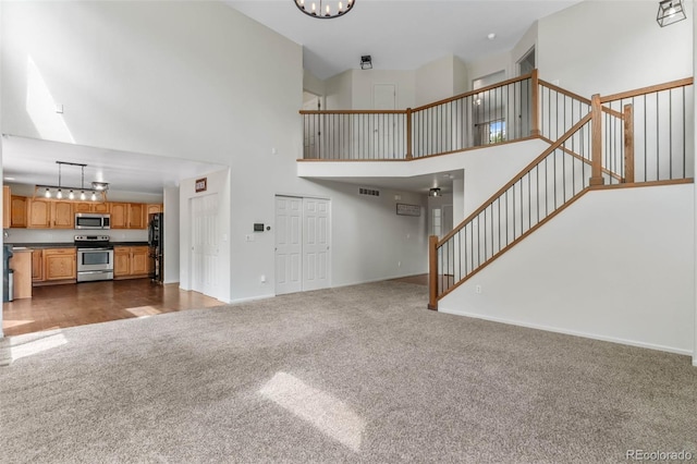 7171 Canyon Way, Frederick, CO 80504 - unfurnished living room with dark colored carpet, a high ceiling, stairway, and a chandelier