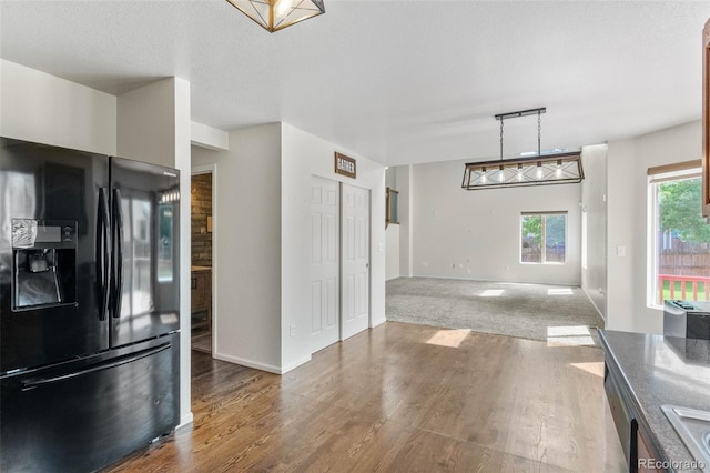 7171 Canyon Way, Frederick, CO 80504 - kitchen featuring black fridge with ice dispenser, wood finished floors, and hanging light fixtures