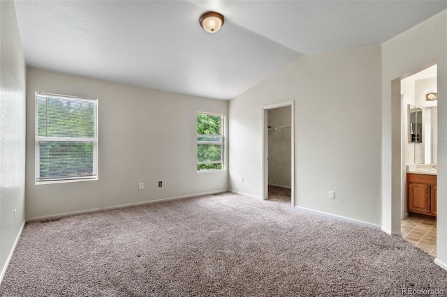 7171 Canyon Way, Frederick, CO 80504 - unfurnished bedroom featuring light carpet, a walk in closet, vaulted ceiling, and connected bathroom