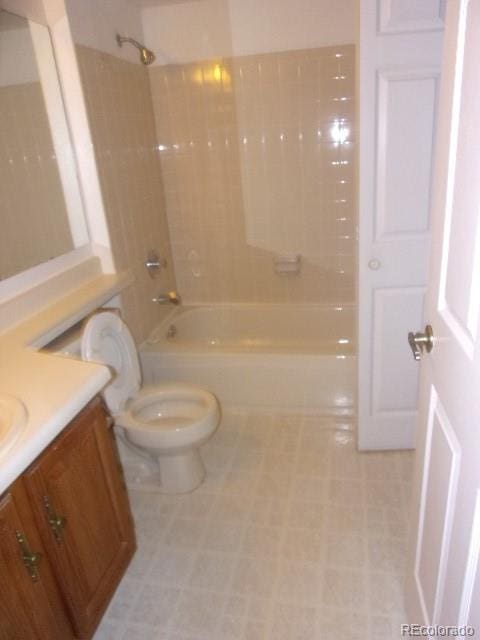 full bathroom featuring vanity, tiled shower / bath combo, and toilet