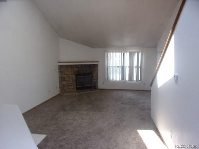 12093 W Cross Dr Unit 308, Littleton, CO 80127 - unfurnished living room featuring a stone fireplace, carpet flooring, and lofted ceiling