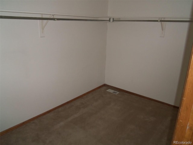 spacious closet with dark colored carpet