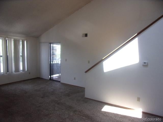 carpeted spare room with high vaulted ceiling