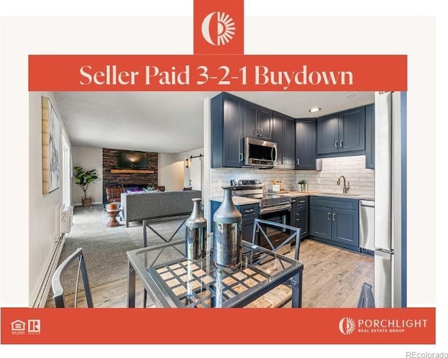 kitchen featuring a fireplace, a sink, decorative backsplash, stainless steel appliances, and open floor plan