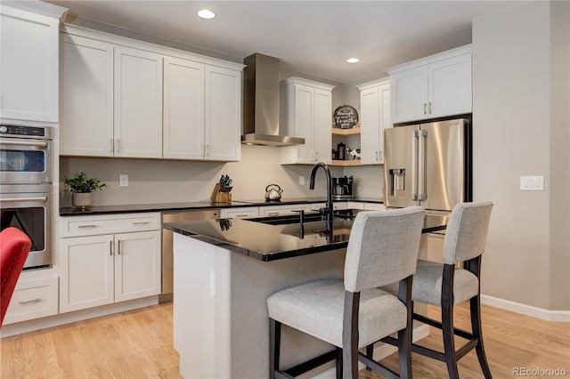 24686 E Florida Ave, Aurora, CO 80018 - kitchen with wall chimney exhaust hood, stainless steel appliances, dark countertops, light wood finished floors, and a kitchen bar