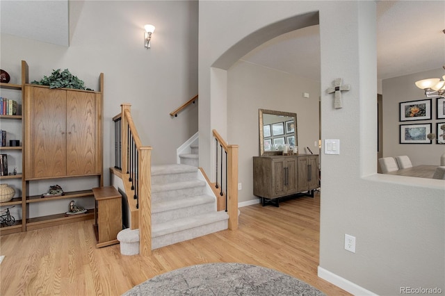 24686 E Florida Ave, Aurora, CO 80018 - staircase featuring arched walkways, wood finished floors, a chandelier, and baseboards
