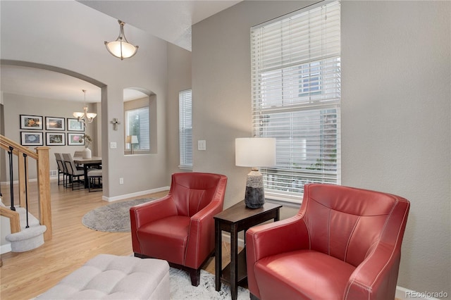 24686 E Florida Ave, Aurora, CO 80018 - living area featuring arched walkways, wood finished floors, baseboards, a chandelier, and stairs