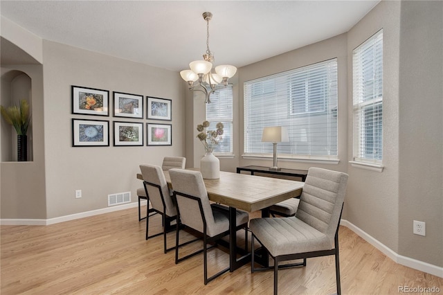 24686 E Florida Ave, Aurora, CO 80018 - dining space with arched walkways, light wood-style floors, a chandelier, and healthy amount of natural light