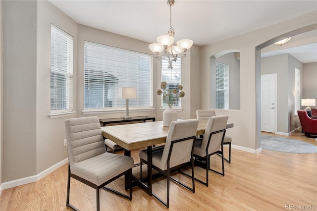 24686 E Florida Ave, Aurora, CO 80018 - dining room featuring arched walkways, a chandelier, light wood-type flooring, and baseboards