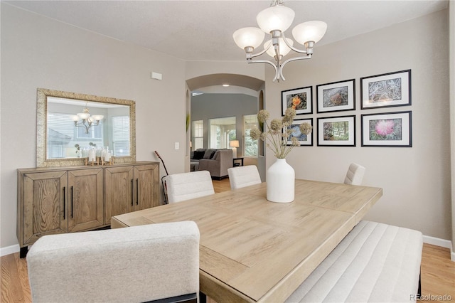 24686 E Florida Ave, Aurora, CO 80018 - dining area featuring a chandelier, arched walkways, light wood-style floors, and baseboards