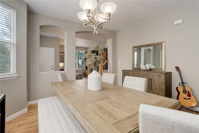 24686 E Florida Ave, Aurora, CO 80018 - dining area featuring arched walkways, a chandelier, light wood finished floors, and baseboards