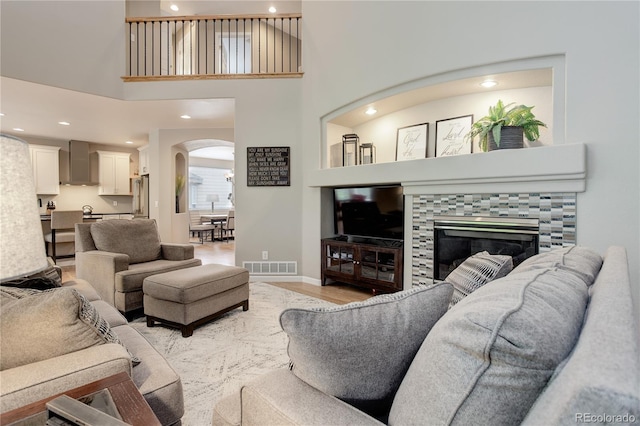 24686 E Florida Ave, Aurora, CO 80018 - living room with arched walkways, light wood-style floors, a tile fireplace, recessed lighting, and baseboards