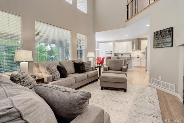 24686 E Florida Ave, Aurora, CO 80018 - living area with light wood-style floors, healthy amount of natural light, baseboards, and a high ceiling
