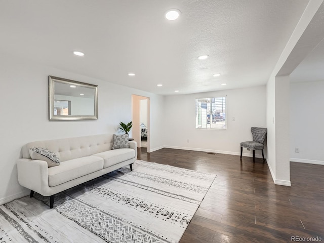 living room featuring a textured ceiling, baseboards, dark wood-type flooring, and recessed lighting