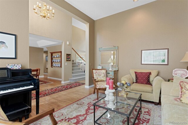 living area with stairway, wood finished floors, a chandelier, a high ceiling, and baseboards