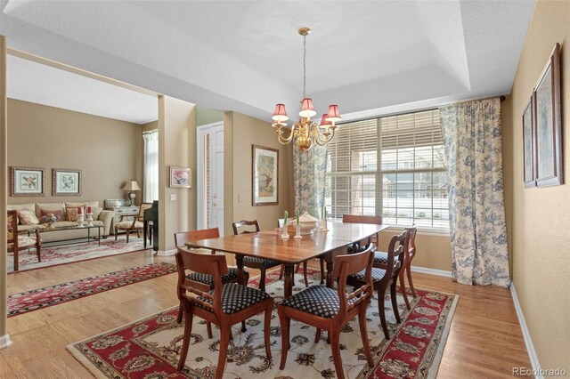 dining area featuring light wood finished floors, a chandelier, and baseboards