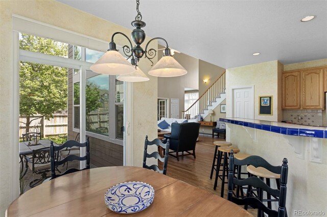 dining room featuring plenty of natural light, dark wood-style floors, stairway, recessed lighting, and a chandelier