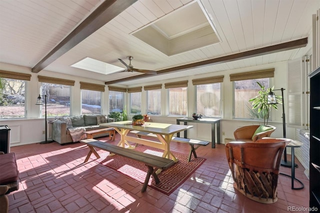 sunroom / solarium featuring ceiling fan, beam ceiling, and a skylight