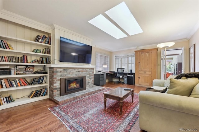 living room featuring crown molding, hardwood / wood-style flooring, a skylight, and a brick fireplace