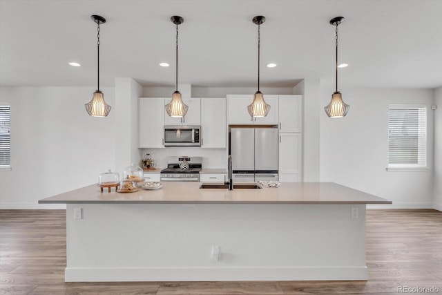 2108 Alcott Way, Broomfield, CO 80023 - kitchen featuring appliances with stainless steel finishes, white cabinets, a kitchen island with sink, light wood finished floors, and recessed lighting