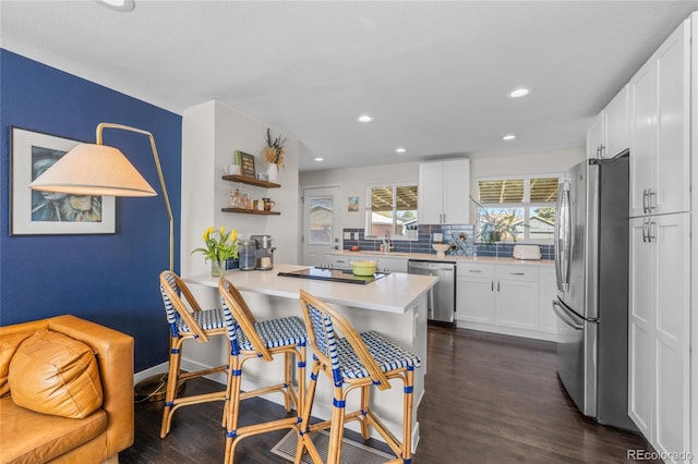 kitchen featuring appliances with stainless steel finishes, dark wood-style flooring, a peninsula, white cabinets, and recessed lighting