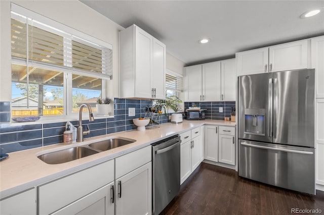 kitchen with stainless steel appliances, a sink, dark wood-style floors, light countertops, and backsplash