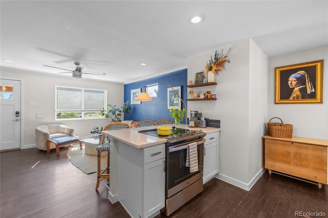 kitchen with stainless steel electric range oven, a kitchen bar, light countertops, recessed lighting, and white cabinetry