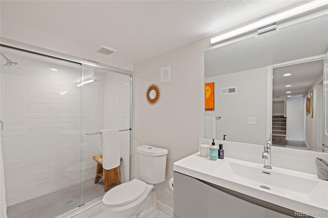 bathroom with toilet, a stall shower, vanity, and a textured ceiling