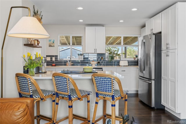 kitchen featuring stainless steel fridge, light countertops, backsplash, white cabinets, and recessed lighting