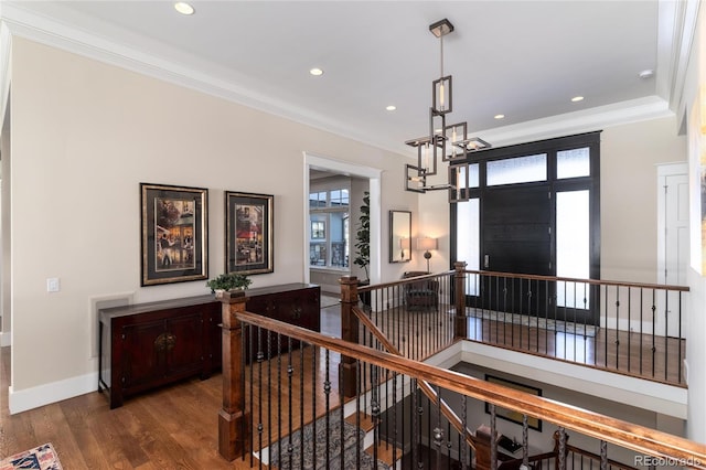 entryway featuring dark wood-type flooring, crown molding, and a notable chandelier