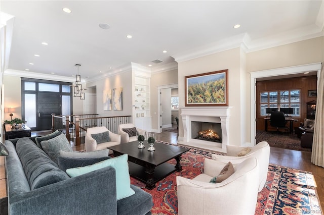 living room with built in shelves, dark hardwood / wood-style flooring, and crown molding