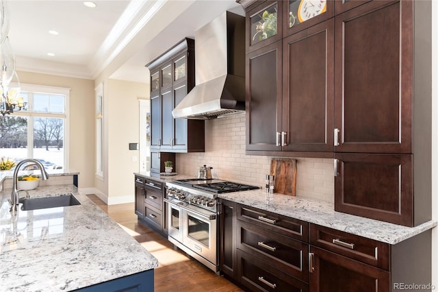 kitchen with dark hardwood / wood-style flooring, light stone counters, sink, wall chimney range hood, and range with two ovens