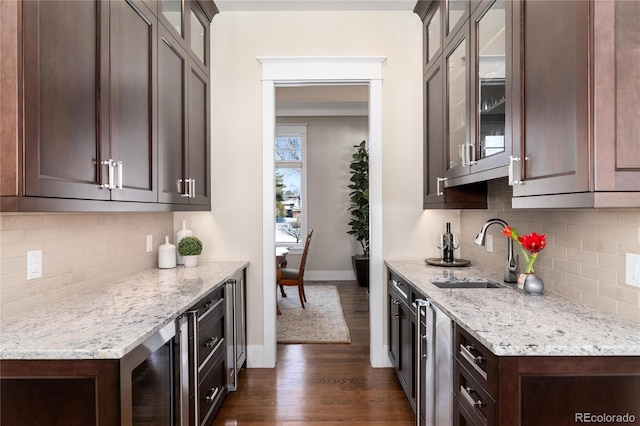 kitchen with light stone counters, dark brown cabinetry, sink, and dark wood-type flooring