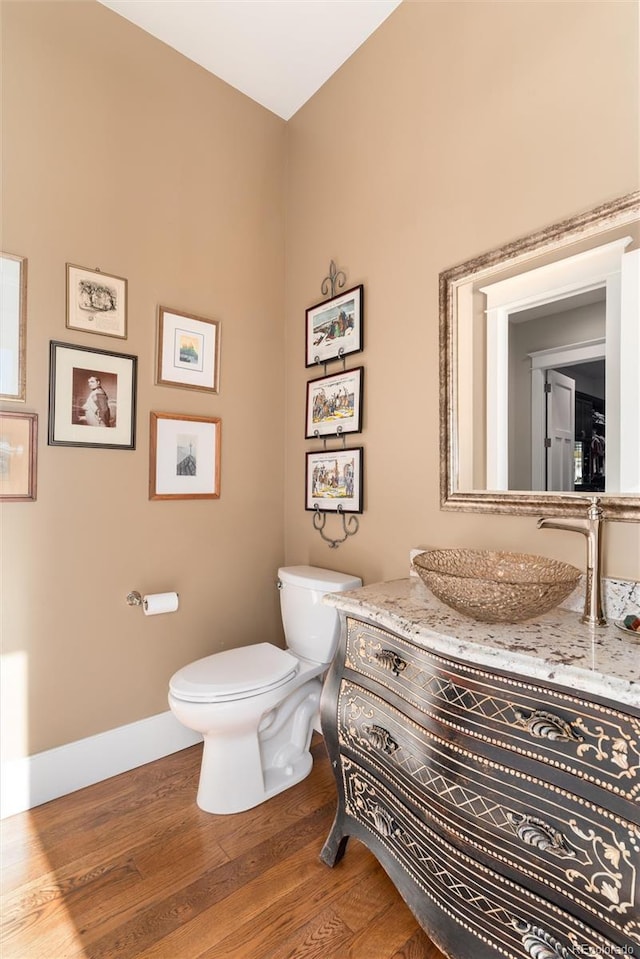 bathroom with wood-type flooring, vanity, and toilet