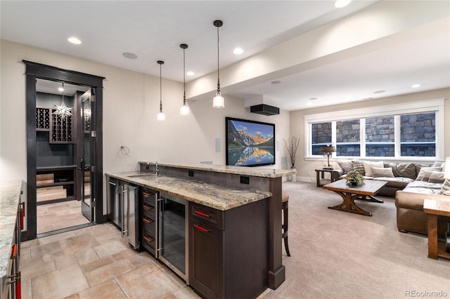 bar featuring light stone countertops, sink, hanging light fixtures, wine cooler, and light carpet