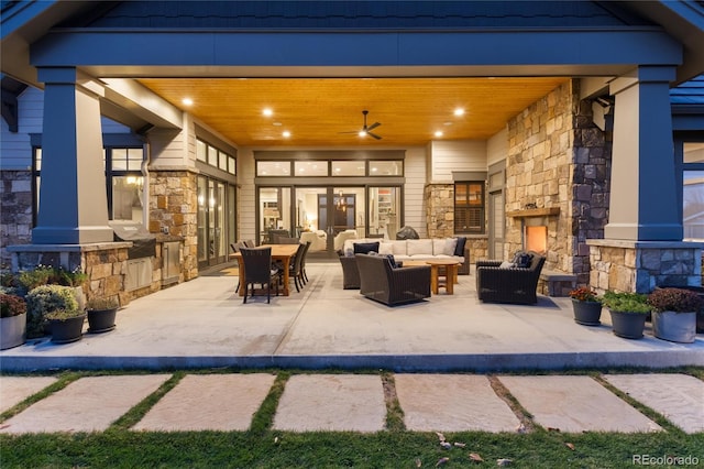 view of patio / terrace with an outdoor living space with a fireplace and ceiling fan