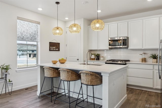 kitchen with a sink, stainless steel microwave, tasteful backsplash, white cabinetry, and stove