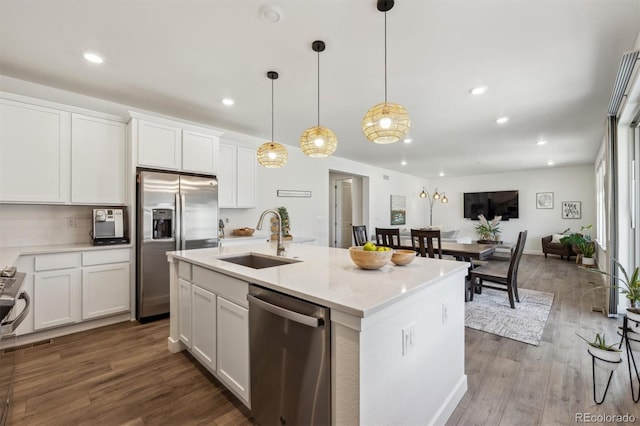 kitchen featuring dark wood-style floors, a center island with sink, a sink, stainless steel appliances, and white cabinetry