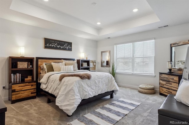 bedroom with visible vents, a tray ceiling, recessed lighting, baseboards, and light colored carpet